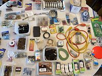 overview of entire lot spread on table showing cords, outlets, screws, tape and assorted hardware