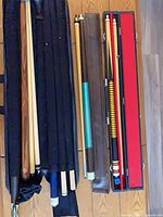 Grouped view of four cues, soft sleeve, brown sleeve, and hard case