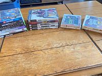 Stack of PS3, Xbox 360, PS2, Wii and 3DS cases spread on table
