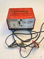 Front view of red MotoMaster 6A charger with attached leads