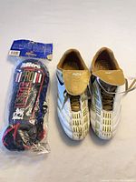 Pair of Rawlings cleats and packaged Mitre shin guards displayed together