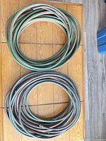 Two coiled welding hoses on wooden table, showing overall quantity and colours