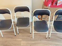 Front view of three black vinyl folding chairs showing overall design and wear