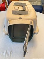 Front view showing open metal wire door, beige top, green bottom, carry handle