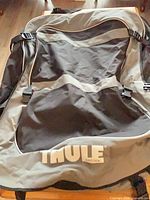 Front view of gray and black Thule cargo bag showing logo and strap system