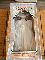 Front of boxed porcelain doll showing complete figure and packaging graphics