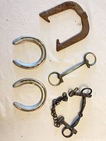 All five vintage steel and iron horse tack items arranged on white background