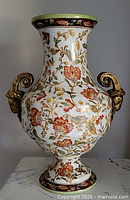 Full view of porcelain vase showing floral decoration and ram head handles