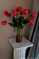 Full view of faux red tulip arrangement on pedestal