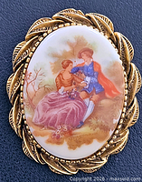 Front view of brooch showing porcelain image and gold-tone frame