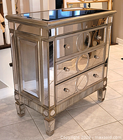 Full view of mirrored dresser front showing three drawers, knobs, top mirror and legs