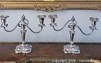 both matching silver-plated candelabras side-by-side on table