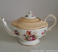 Right side view of teapot showing floral design, spout, handle, footed base