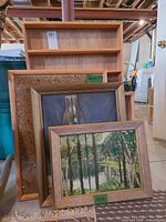Group shot showing wooden shelf with lot tag behind paintings and cork board