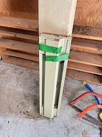 boxed beige baseboard heater strapped with green tape