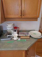 Countertop view of coffeemaker, French press, bowls, placemats, dripper and frother case