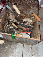 Overview of wooden toolbox with assorted masonry tools inside