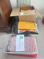 Cardboard box and two bins of fabric