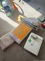 Lot overview showing Scan ‘n Sew case, two pressing boards, cardboard box and detergent unrelated