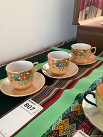 Three matching Japanese lustreware teacups with saucers displayed on cloth