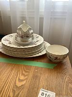 Stack of dinner plates with gravy boat and underplate on top, platter beneath