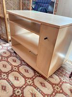 front angled view showing open shelves, side door handle, light wood finish