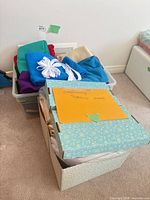 Overview of plastic bin with fabrics and ribbon beside box of patterns