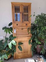 Full view of pine secretary desk showing glass upper cabinet, drop-down desk, and lower cupboard