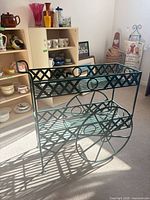 Full view of green metal plant cart showing shelves, wheels, handle