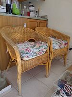 Front view of two rattan armchairs with floral cushions