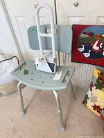 Full view of shower chair with safety rail resting on seat