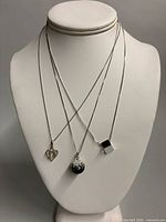 Three necklaces displayed on bust to show design and pendants