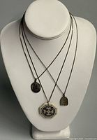 Front view of three sterling necklaces with pendants on display bust