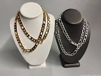 Two gold-tone Vera and Figaro necklaces on white bust, two silver-tone on black bust