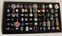 Full tray view showing over 60 assorted costume rings in various styles and finishes