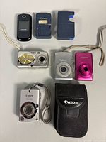 Group shot of four cameras, two chargers, Canon case