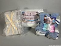 Three packaged items: comforter, sherpa throw, towel set
