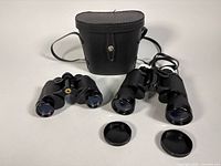 Overall view showing both binoculars, carrying case, and lens caps