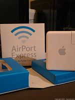 Front view of AirPort Express device beside box and tray