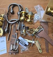 All items spread on table: brass and nickel doorknobs, curtain holdbacks, latch parts, screws