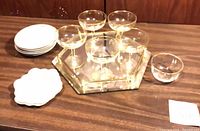 Lot overview showing glass coupes on mirrored tray, stacks of plates and glass bowl