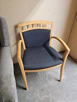 Front view of armchair showing light wood frame and black patterned upholstery