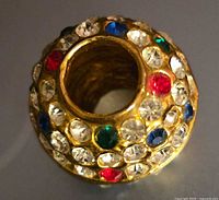 Top view of spherical gold-tone bead showing large center hole and multicolour rhinestones