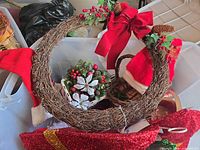 Overview of tub showing grapevine wreath with bow, Santa hat, wicker basket, floral pick and glitter sleigh accent