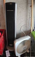 Front view of Lasko tower heater beside Massey table fan showing overall condition and cords