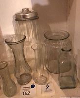 Group of clear and smoked glass vessels on shelf