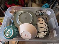 Overall view of bin showing bowl, plates, lantern, platter, mug and rack