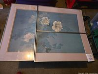 Two large blue-toned floral prints in silver frames placed side by side