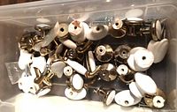 Bin containing numerous porcelain-inset knobs and pulls