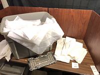 Tote filled with white linens and license plate frame on table